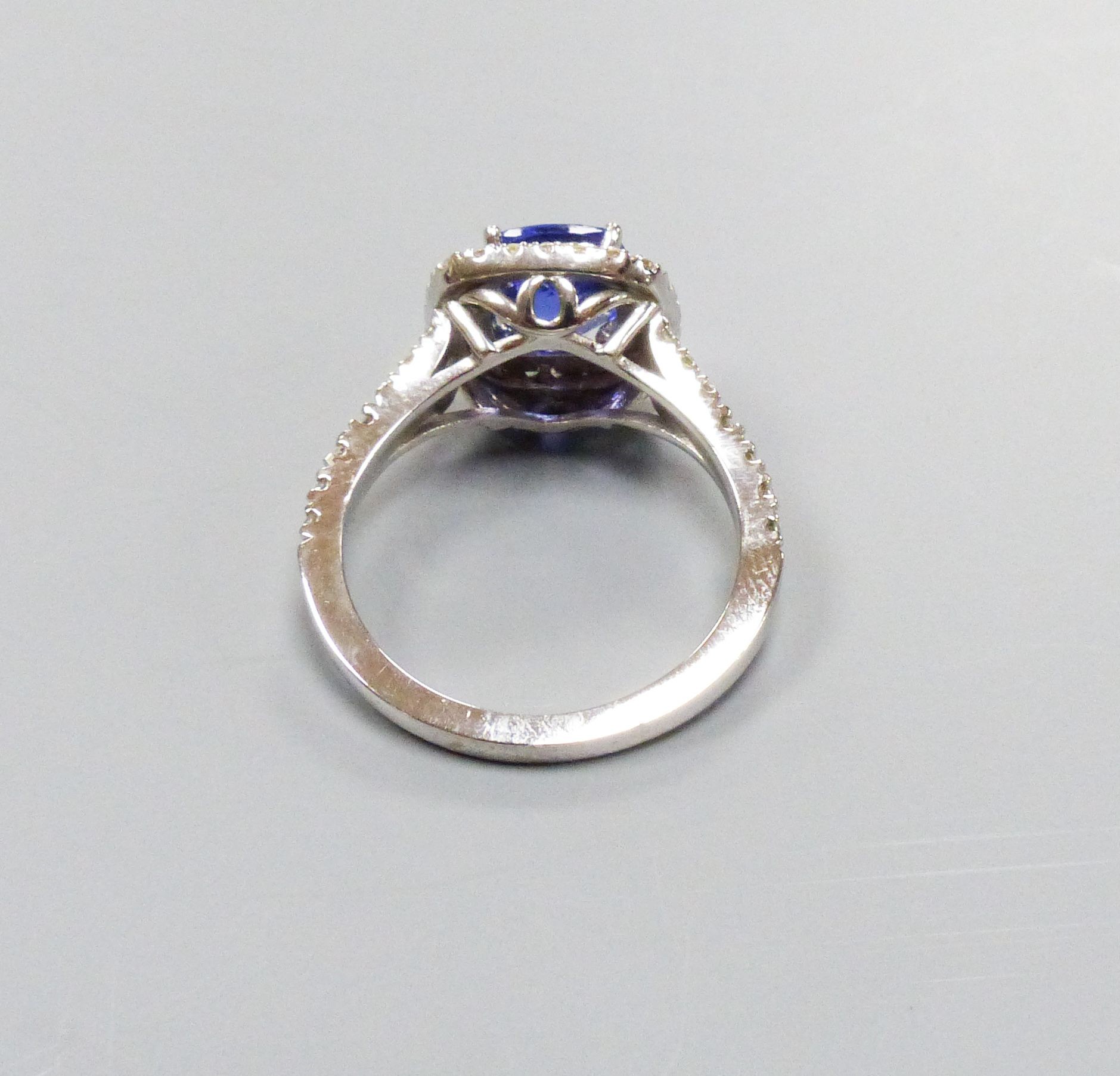 A modern 14k white metal, tanzanite and diamond set square cluster ring, with diamond set split shoulders, size M/N, gross weight 4.2 grams, the tanzanite weighing 1.63ct